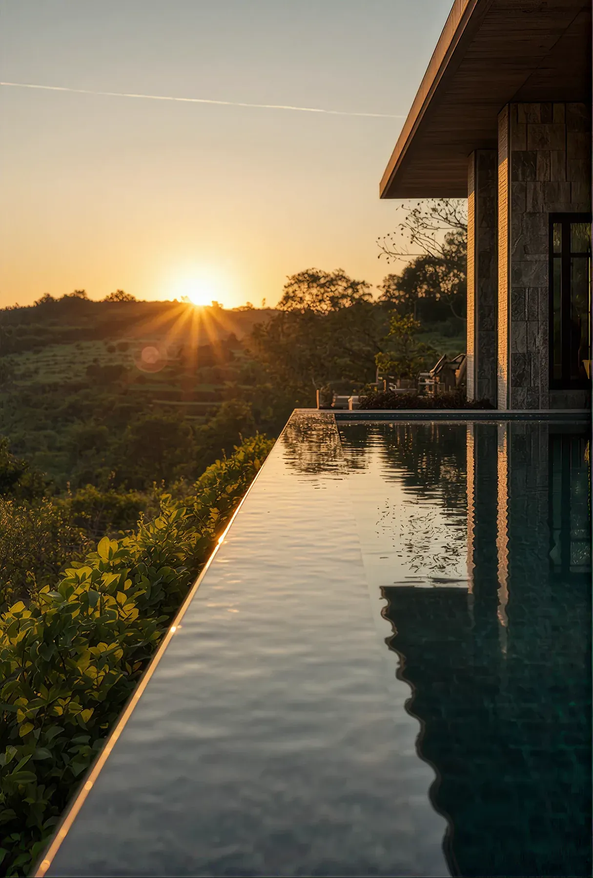 Infinity pool at golden hour beside a modern pavilion